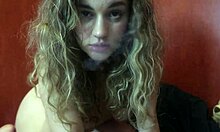 Uma linda loira de seios grandes faz sexo oral enquanto fuma um cigarro